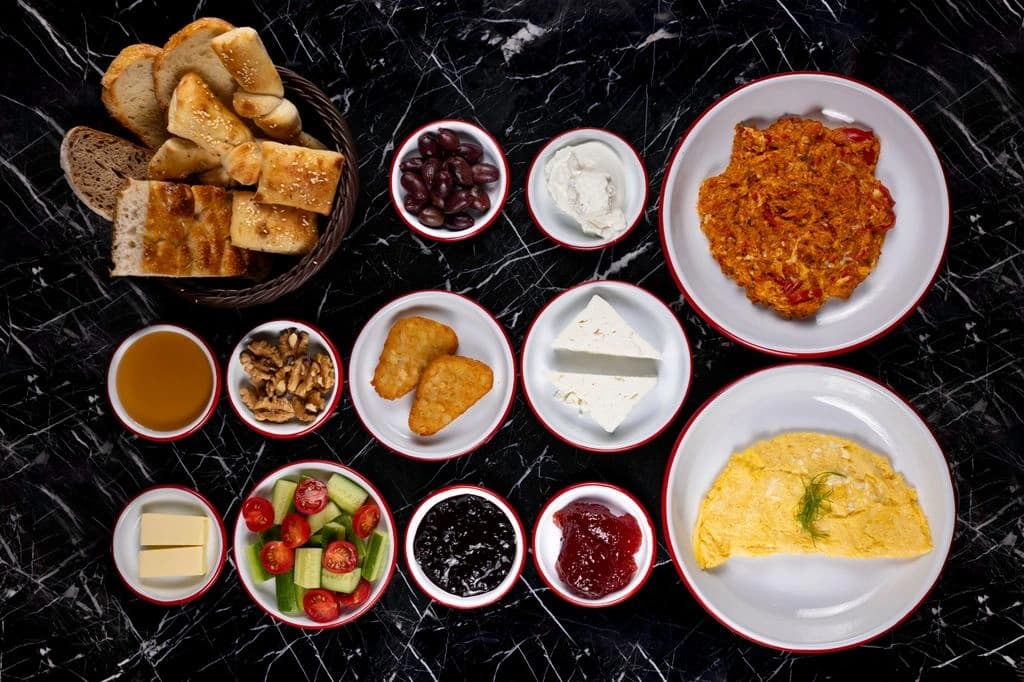 Double breakfast combo plate with shakshuka, omelette, Greek yogurt, fresh fruits, and artisan bread