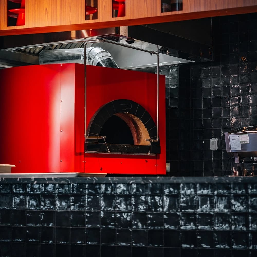 Chef preparing authentic Italian pizza in traditional wood-fired brick oven